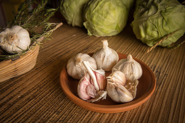 Plate with garlic tubers standing on a wooden table