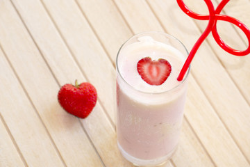 Strawberry smoothie and strawberry fruit on white wood.