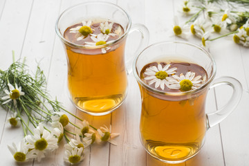Cup of tea and chamomile flowers on wooden background