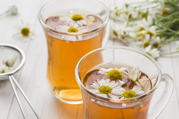 Cup of tea and chamomile flowers on wooden background
