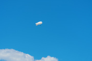 Large white air balloon in shape of an airship in the blue sky