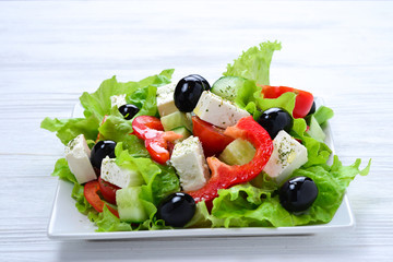 Greek salad on a white wooden background. Space for text or design.