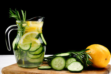 Cold and refreshing detox water with lemon, cucumber, rosemary and ice in glass jar. Copyspace. Banner