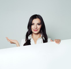 Fototapeta premium Business woman holding white blank paper banner background and showing empty hand. Young woman smiling. Product placement, infographic and presentation concept