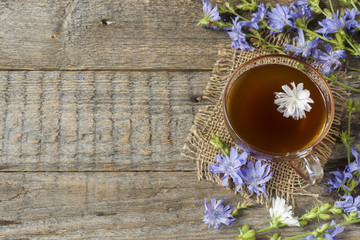Obraz na płótnie Canvas Chicory drink in Cup and flowers on rustic wooden background. Medicinal plant Cichorii.