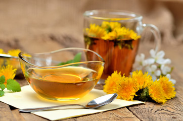 Dandelion honey, herbal tea, spring flower, spoon and dandelion head around