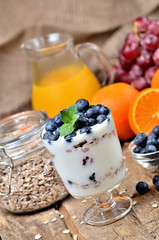 Bio yogurt with oatmeal, fresh blueberries, mint and orange juice, grapes in background vertical photo
