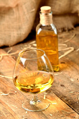 Glass of cognac on rustical wooden background and bottle in background vertical photo