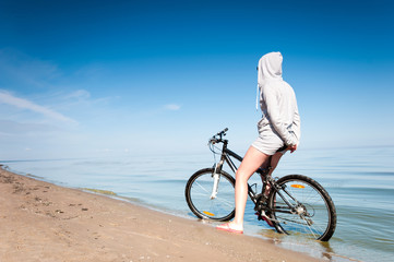 Fototapeta premium Young sporty lady resting from riding bicycle on the beach