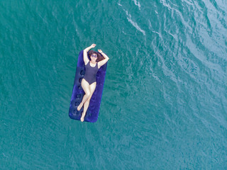 woman on mattress in azure water. overhead view. copy space