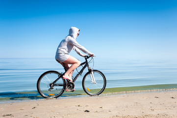 Young teenage sporty girl riding bicycle at the seaside