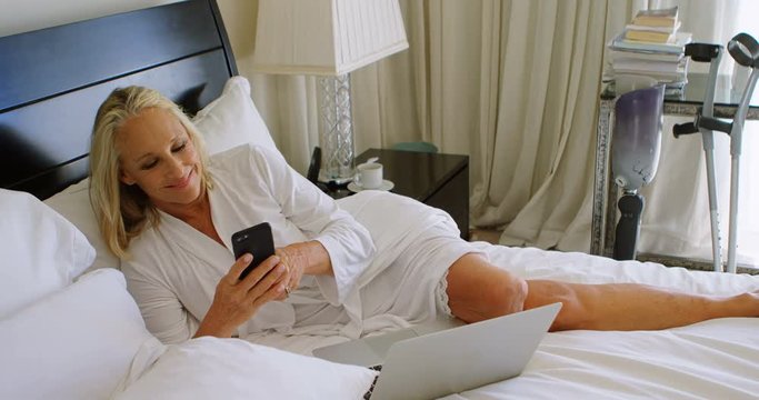 Disabled woman using mobile phone in bedroom 4k