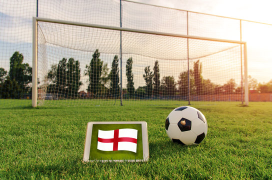 Soccer ball in front of empty goal and flag of England on digital tablet on the grass ;  Bright future