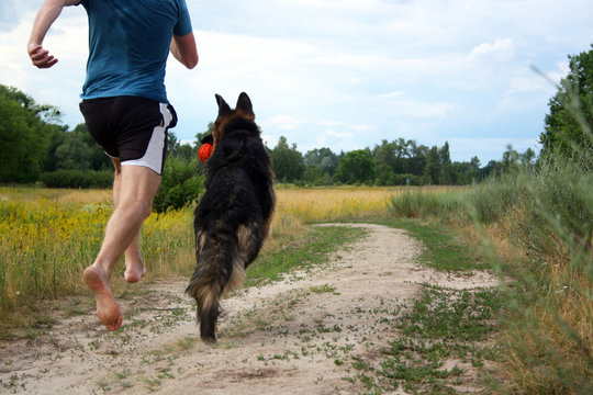 Young Man Jogging Barefoot With His Dog