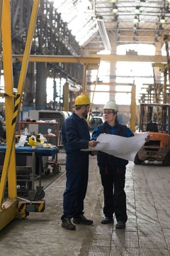 Technician discussing blueprint with his colleague