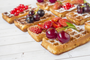 Homemade waffles with summer berries on a light table. Selective focus