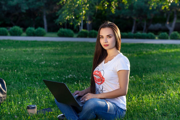 Young woman using computer on green grasses in the park. Education learning or freelance working outdoor or relaxation concept idea background.