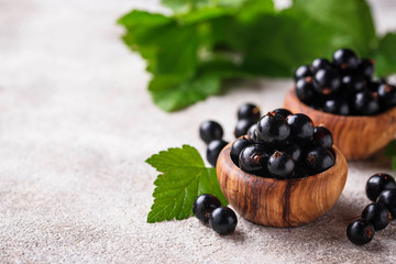Black currant with leaves in wooden bowls