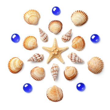 Pattern in the form of a circle made of shells, starfish and blue glass beads isolated on white background