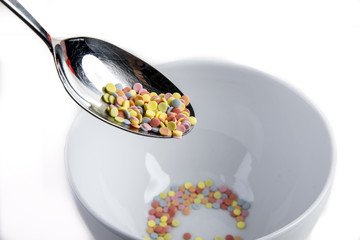 sweet round candys for decoration on a spoon over a white bowl