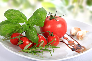 Pomidor czerwony, malinowy i koktajlowy, bazylia, rozmaryn i czosnek na talerzu. - obrazy, fototapety, plakaty