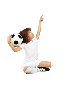 Photo of smiling preschool boy in sportswear holding soccer ball and pointing thumb up - posing on studio. Isolated on white Copy Space