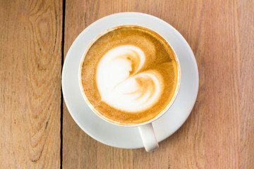 Coffee with milk cream on wooden table, top view