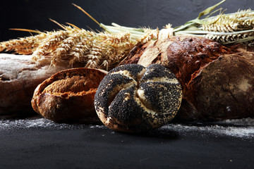 Different kinds of bread and bread rolls on board from above. Kitchen or bakery
