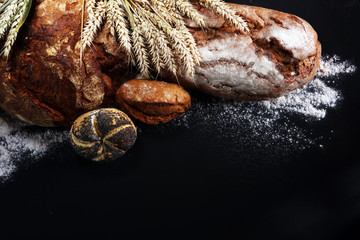 Different kinds of bread and bread rolls on board from above. Kitchen or bakery
