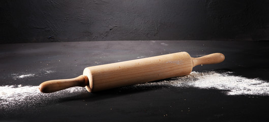 Baking background with the rolling pin with flour. On the dark table. Free space for text