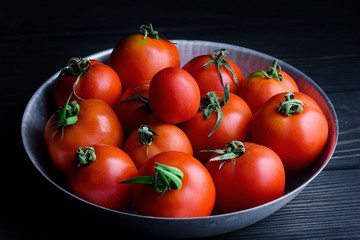 Ripe tomatoes on a dark table in a plate