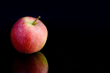 One apple on a black background with reflection