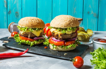 Tasty grilled homemade burgers with beef, tomato, cheese on concrete background