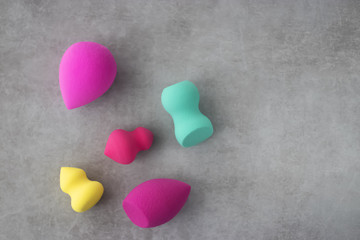 Fototapeta premium Multicolored cosmetic sponges on a gray concrete background.