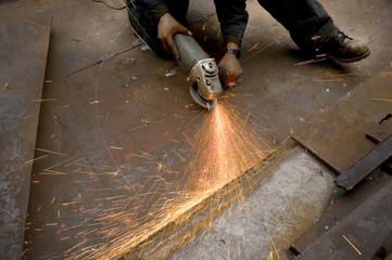 Man Grinding in metal workshop Heat sparks from the iron grinding process 