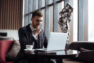 Young man drawing template for the web site associated with digital marketing, current trends and tendencies of UX / UI design. Businessman who rules his company remotely, like a freelancer