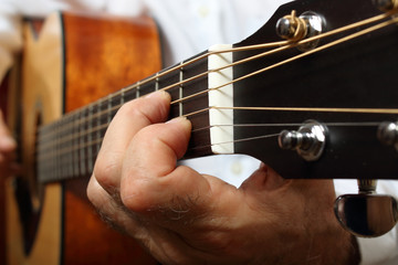 The musician in a white shirt playing acoustic guitar