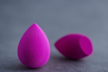 Multicolored cosmetic sponges on a gray concrete background.
