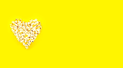 Heart shaped white fluffy popcorn on yellow background