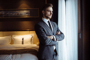 Fototapeta premium Young handsome man relaxing at his apartment in a hotel after business meeting. Business trip. Booking hotel during your vacation. Businessman in luxury room of the expensive beautiful hotel. 