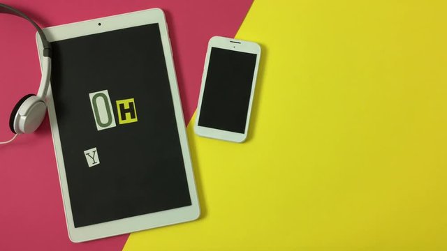 Telefono, tablet y auriculares sobre fondo rosa y amarillo.