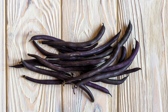 Beans of purple beans on a wooden background. Spinach beans. Asparagus beans