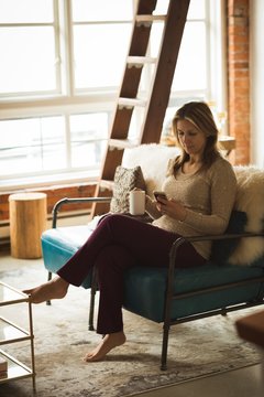 Woman using mobile phone while having coffee
