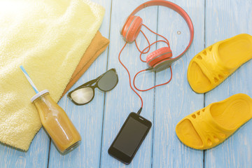 phone with headphones and sunglasses on a blue background, on a summer beach.