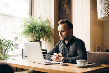 Fototapeta premium Adult serious man has business conversations using on-line mobile application. Developer innovational business web applications in the internet. Stylish guy. Business portrait. Cloud technologies.