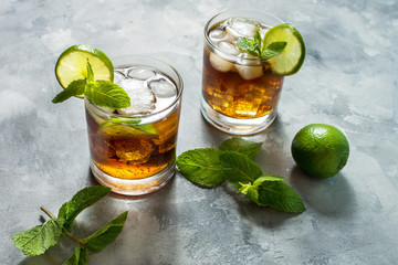 Rum and cola. Cuba Libre drink with lime and ice on rustic concrete table