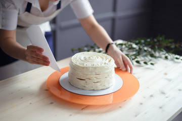 Obraz na płótnie Canvas confectioner in a white apron on a dark background with a cake