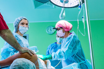 cosmetic liposuction surgery in actual operating room setting showing surgeons group during operation