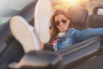 Happy young woman enjoying her convertible car