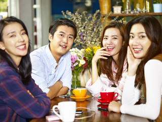 happy young asian adults looking at camera smiling in coffee shop